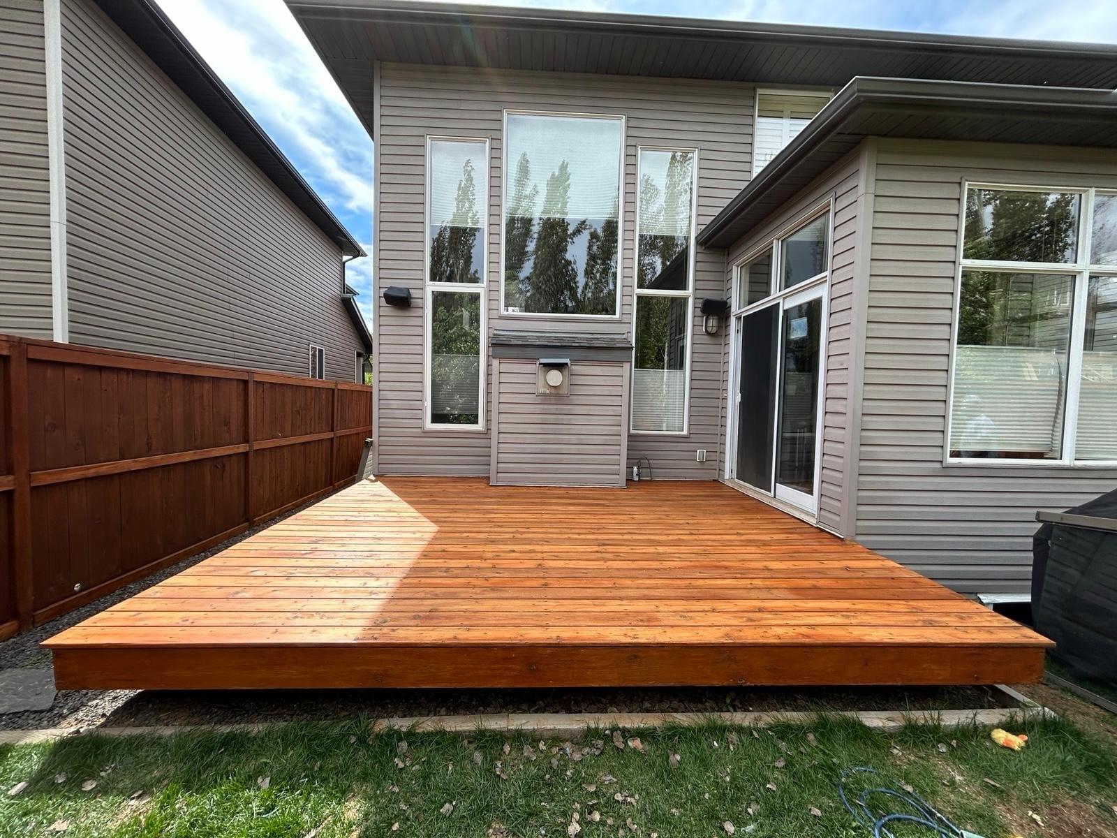 Freshly stained backyard deck beside a stained fence