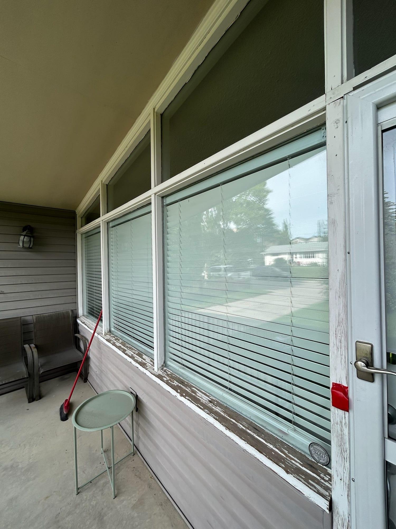 Porch window frames and sills with worn, flaking paint