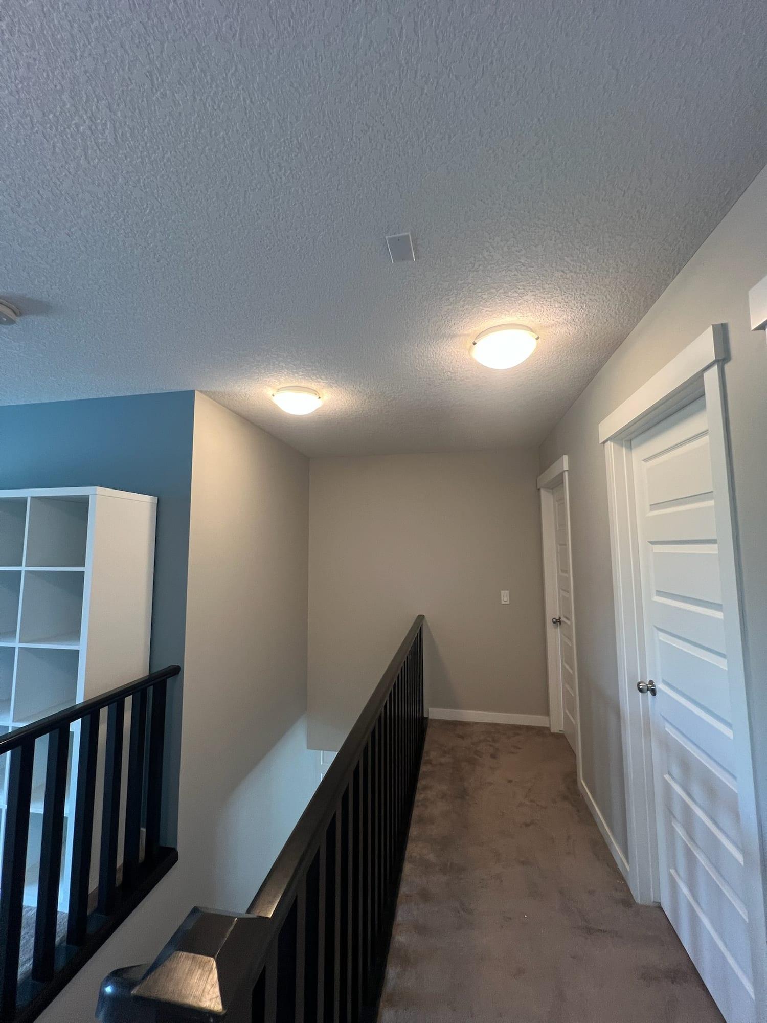 Upstairs landing with light grey walls, white doors and trim, and a blue accent wall
